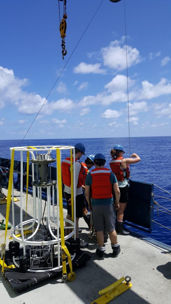 Scientists standing on the side of a ship in the open ocean
