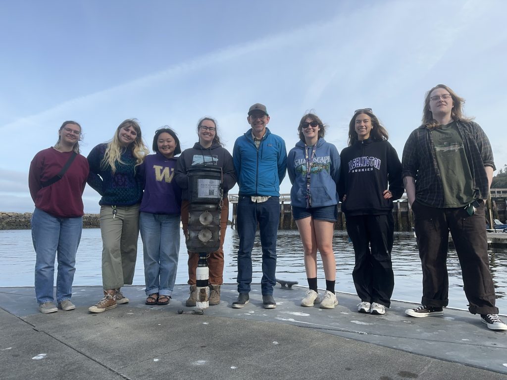 A group of people on a dock stand posing for a photo.