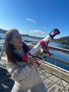 Celeste stands holding a piece of equipment