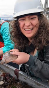 Kaiya wears a hard hat while holding a sea organism