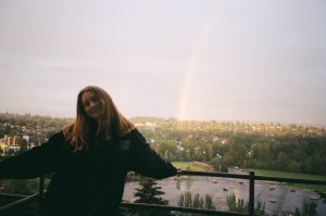 Megan Fellstrom stands on a deck with a rainbow in the background