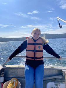 Jenna stands on a boat wearing a life hacket