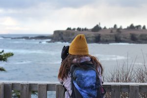Mollie is pictured from behind using binoculars to look out over the coast.