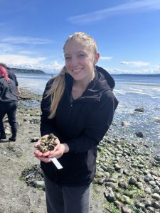 Jenna holds shells on a beach
