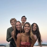 A group of people pose for a photo with calm sea in the background
