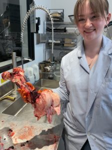 Lauren holds a meaty boat in a lab while conducting a necropsy.