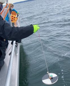 Lily Peterson holds equipment over the side of a boat