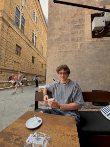 Liam De Vries sits at an outdoor cafe with a coffee