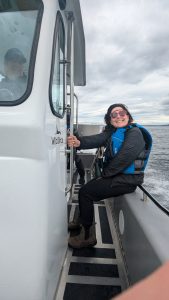 Mollie Ball sits at the back of a boat smiling