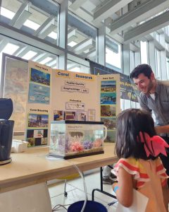 Dylan Strauss at the coral exhibit at the SEAS Open House, speaking to a child