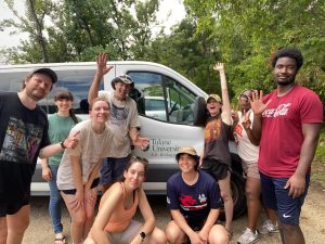 A group of people stand cheering in front of a white van