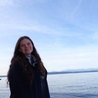 Ellie Thomas stands for a photo with a calm sea in the background