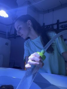 Charly Cooper holds an instrument to clean a tank at the New England Aquarium.