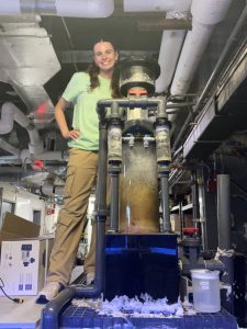 Charly Cooper stands next to a protein skimmer machine, which filters out waste and uneaten food from aquarium tanks.