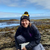 woman in field in front of tide pools