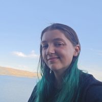 Woman with teal hair in front of water