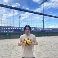 Man holding volleyball on sand court