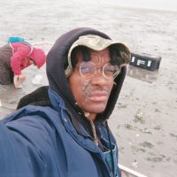 Man sampling in mud flats with mud on face