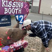 Man kissing pig at kissing booth
